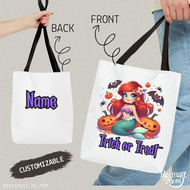 May include: White tote bag with black handles. The front features a cartoon mermaid with red hair, sitting on pumpkins, with bats and spiders. Text reads "Trick or Treat". The back has the word "Name" in purple.