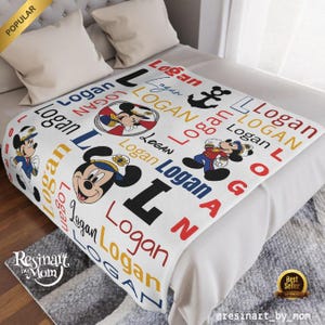 Op de afbeelding: Een wit fleece deken met een nautisch thema met Mickey Mouse. Het deken is gepersonaliseerd met de naam "Logan" die door het hele ontwerp heen wordt herhaald. Het deken heeft een rood-wit-blauw kleurenschema met een anker en Mickey Mouse in een matrozenpak.