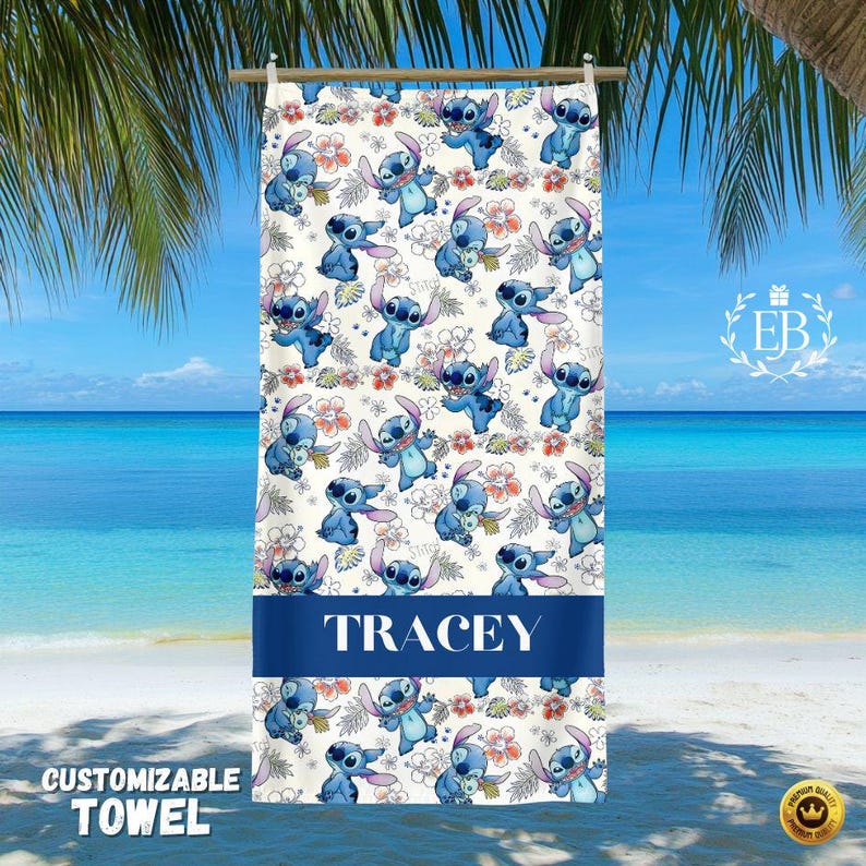K&ouml;nnte beinhalten: Ein anpassbares Strandtuch mit einem sich wiederholenden Muster eines blauen Zeichentrickcharakters und roten und orangefarbenen Blumen auf cremefarbenem Hintergrund. Das Handtuch hat ein marineblaues Band mit dem Namen "TRACEY" in Wei&szlig;. Der Text "CUSTOMIZABLE TOWEL" ist unten aufgedruckt.