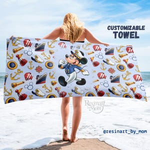 May include: A blue and white beach towel with a nautical theme. The towel features a cartoon Mickey Mouse dressed as a sailor, anchors, ships, and other nautical symbols. The text "CUSTOMIZABLE TOWEL" is at the top of the image.
