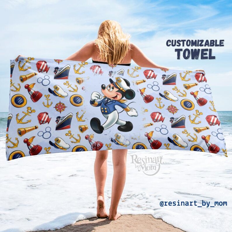May include: A blue and white beach towel with a nautical theme. The towel features a cartoon Mickey Mouse dressed as a sailor, anchors, ships, and other nautical symbols. The text "CUSTOMIZABLE TOWEL" is at the top of the image.