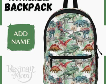 May include: A white backpack with a colourful dinosaur pattern. The backpack has a black zipper and a black adjustable strap. The text "CUSTOMIZABLE BACKPACK" is at the top of the image. The text "ADD NAME" is in a green box. The text "Resinart by Mom" is in a white box with a green border. The text "@resinart_by_mom" is at the bottom of the image.