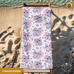 May include: A beach towel with a repeating pattern of cartoon characters in shades of pink and blue, with small flowers and leaves on a white background. The towel is displayed on a wooden beach chair on a sandy beach. The word "Customizable" is visible.