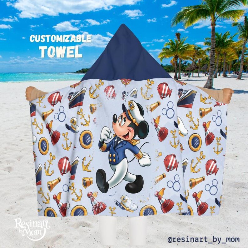 May include: A blue hooded towel with a white background featuring a cartoon Mickey Mouse dressed as a sailor. The towel has a nautical theme with anchors, ships, and other nautical symbols.