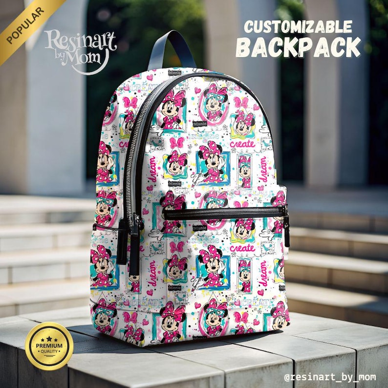 May include: A white backpack with a black zipper and a colorful print of Minnie Mouse. The print includes the words "dream" and "create" in a handwritten style. The backpack is customizable.