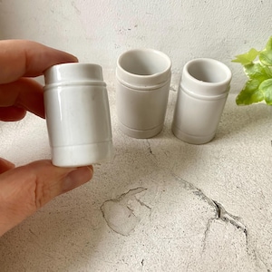 Op de afbeelding: Drie witte keramische bekers met een afgeronde vorm en een licht uitlopende rand. De bekers zijn allemaal even groot en hebben een gladde, glanzende afwerking.