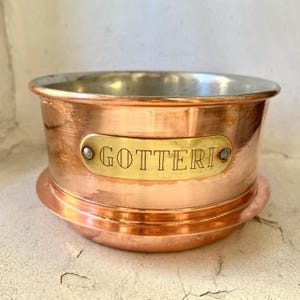 May include: A copper bowl with a brass band and a brass plaque that reads "GOTTERI".