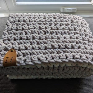 May include: A soft, gray and white crocheted throw blanket with a brown leather tag that says "IF".