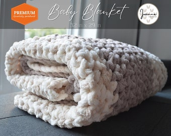 May include: A soft, cream and brown crocheted baby blanket, folded on a gray couch. The blanket is 32 inches by 29 inches. The text "Baby Blanket" and "32 in x 29 in" is printed on a white background.