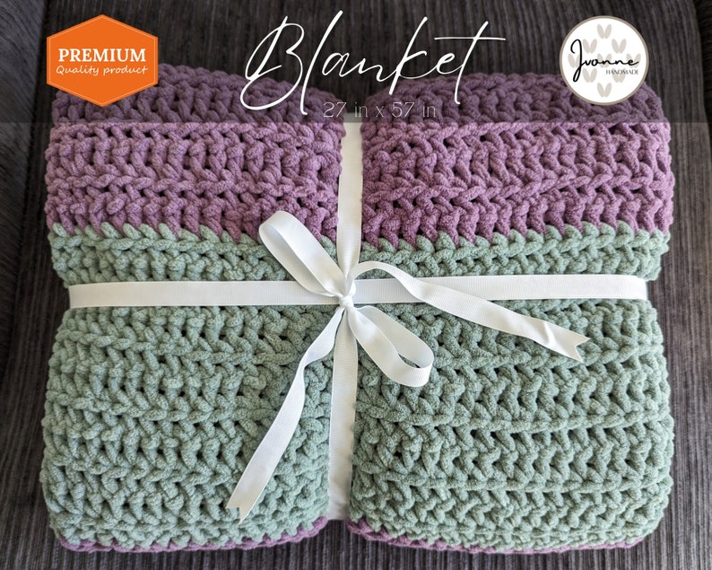 K&ouml;nnte beinhalten: Eine geh&auml;kelte Decke in Gr&uuml;n und Lila, die mit einem wei&szlig;en Band gebunden ist. Die Decke ist 27 Zoll mal 57 Zoll gro&szlig;. Der Text "Blanket" und "27 in x 57 in" ist auf einem wei&szlig;en Etikett aufgedruckt.