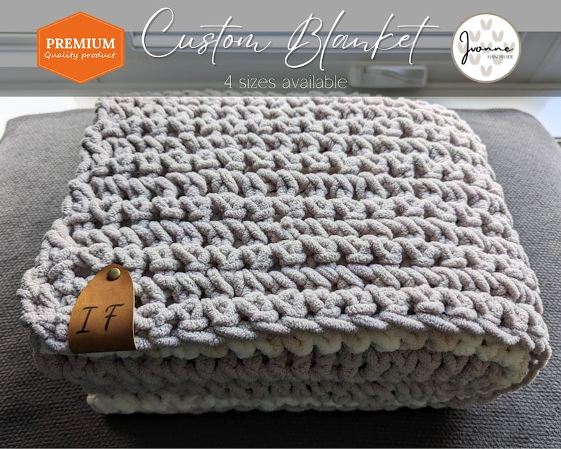 May include: A soft, gray and white crocheted blanket with a leather tag that says "IF". The blanket is on a gray couch. The text "Custom Blanket" and "4 sizes available" is written above the blanket. The text "Premium Quality Product" is in the top left corner of the image. The text "Joanne Handmade" is in the top right corner of the image.