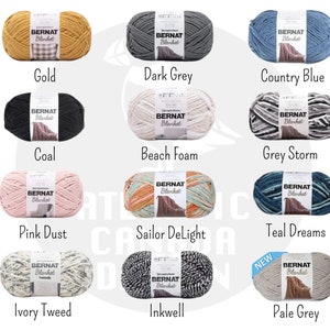 May include: A collection of yarn skeins in various colors, including gold, dark grey, country blue, coal, beach foam, grey storm, pink dust, sailor delight, teal dreams, ivory tweed, inkwell, and pale grey. Each skein features the Bernat Blanket brand label.