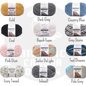 May include: A collection of yarn skeins in various colors, including gold, dark grey, country blue, coal, beach foam, grey storm, pink dust, sailor delight, teal dreams, ivory tweed, inkwell, and pale grey. Each skein features the Bernat Blanket brand label.
