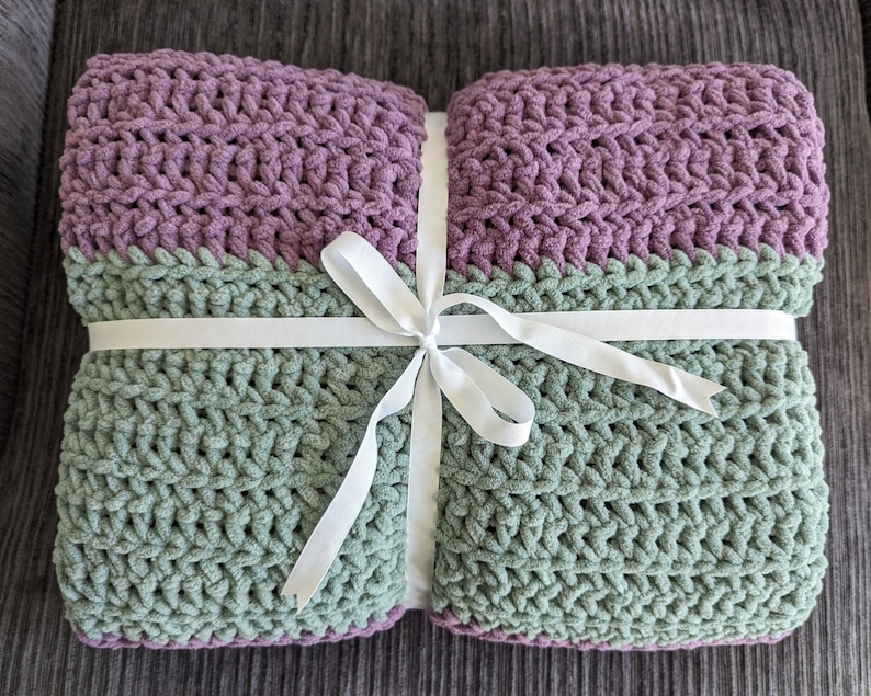 May include: A green and purple crocheted throw blanket tied with a white ribbon.