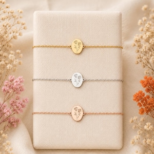 Puede incluir: Tres delicadas pulseras de cadena con dijes ovalados. Cada dije presenta un grabado floral de l&iacute;neas finas. Las pulseras se presentan en tonos oro, plata y oro rosa, centradas cada una sobre un soporte de exhibici&oacute;n rectangular.