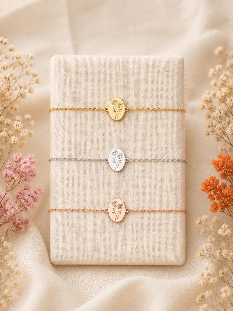 Puede incluir: Tres delicadas pulseras de cadena con dijes ovalados. Cada dije presenta un grabado floral de l&iacute;neas finas. Las pulseras se presentan en tonos oro, plata y oro rosa, centradas cada una sobre un soporte de exhibici&oacute;n rectangular.