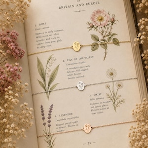 Puede incluir: Tres delicadas pulseras de cadena de metal con peque&ntilde;os dijes ovalados grabados con dise&ntilde;os florales. Una pulsera dorada muestra una rosa, una pulsera plateada muestra lirios de los valles y una pulsera de oro rosa presenta lavanda.
