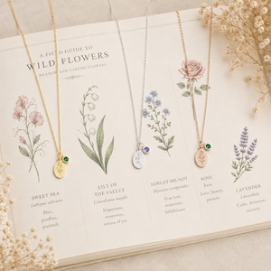 May include: Three necklaces with oval pendants featuring engraved floral designs and small round birthstone charms. One necklace is gold-toned with a green stone, one is silver-toned with a purple stone, and one is rose gold-toned with a green stone.