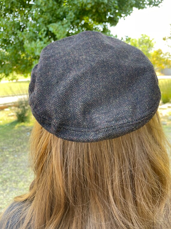 Fisherman's cap composed of herringbone pattern wool blend fabric. Faux leather band with side stitch detail