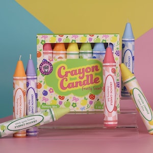 May include: A set of eight crayon-shaped candles in various colors and fruity scents. The candles are arranged in a box with a colorful design and the text "Crayon Candle Fruity Scents".