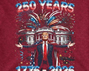 May include: Maroon t-shirt with a graphic featuring the text "250 YEARS" above an illustration of the White House and a person in a suit. The text "1776-2026" is below the illustration. Fireworks and patriotic colors are used.