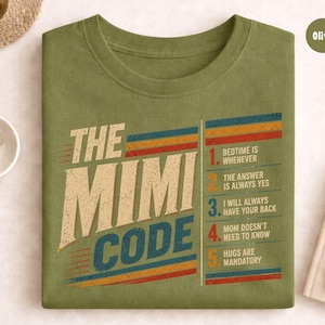 Könnte beinhalten: Olivgrünes T-Shirt mit dem Aufdruck "THE MIMI CODE" im Retro-Stil. Das Design enthält eine Liste von Regeln in einem vertikalen Streifen mit Texten wie "Bedtime is Whenever" und "Hugs are Mandatory".
