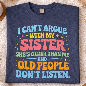 May include: A heather navy blue t-shirt featuring the text: "I can't argue with my sister, she's older than me and old people don't listen." The text is in a colourful, retro style. The shirt is displayed on a textured surface.