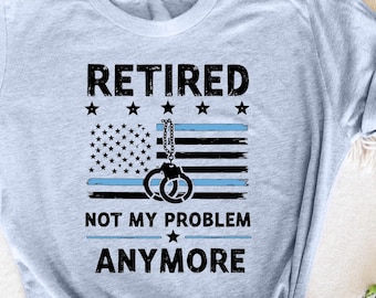 Könnte beinhalten: Ein hellblaues T-Shirt mit einem schwarz-blauen amerikanischen Flaggen-Design. Der Text "Retired Not My Problem Anymore" ist auf dem Shirt aufgedruckt.