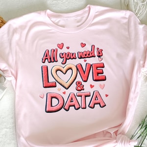 Op de afbeelding: Roze T-shirt met de tekst "All you need is LOVE & DATA" in rood en wit met een hartvormige afbeelding.