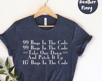 Peut inclure: T-shirt bleu marine chiné avec le texte blanc "99 Bugs In The Code, Take One Down, And Patch It Up, 117 Bugs In The Code". Le t-shirt est présenté sur un cintre en bois.