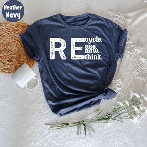 May include: A heather navy blue t-shirt with a white distressed graphic that reads "REcycle. use. new. think."