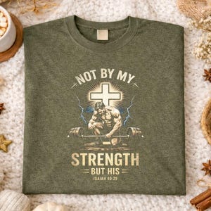 K&ouml;nnte beinhalten: Olivgr&uuml;nes T-Shirt mit einer Grafik eines Gewichthebers, der vor einem Kreuz kniet, mit dem Text "NOT BY MY STRENGTH BUT HIS Isaiah 40:29". Das T-Shirt ist aus einem weichen Material gefertigt.