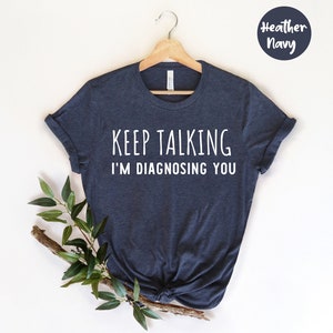 May include: A heather navy blue t-shirt with the text "Keep Talking I'm Diagnosing You" printed in white.