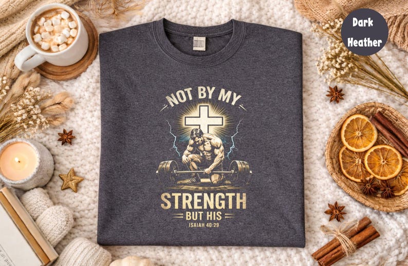 K&ouml;nnte beinhalten: Dunkelgraues meliertes T-Shirt mit einer Grafik mit einem Kreuz, einem Gewichtheber und dem Text "NOT BY MY STRENGTH BUT HIS Isaiah 40:29". Das Shirt hat einen Rundhalsausschnitt.