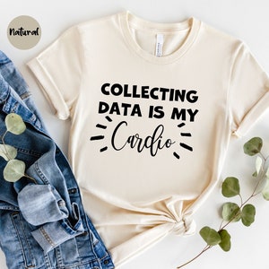 May include: A cream coloured t-shirt with the text "COLLECTING DATA IS MY CARDIO" printed in black.