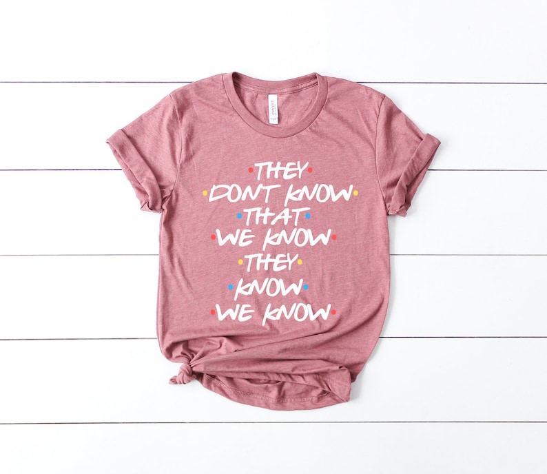 May include: A pink t-shirt with the text "They don't know that we know they know we know" in white with colorful dots.