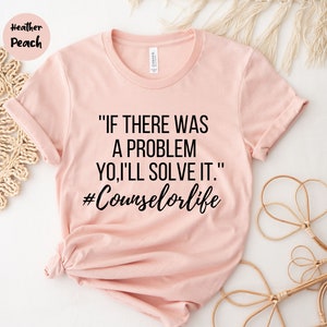 May include: A pink t-shirt with the text "IF THERE WAS A PROBLEM YO,I'LL SOLVE IT." and the hashtag #Counselorlife printed in black.