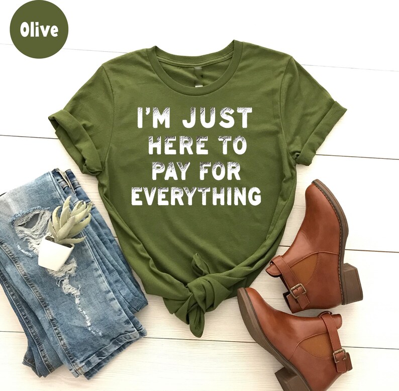 K&ouml;nnte beinhalten: Olivengr&uuml;nes T-Shirt mit dem Text "I'm just here to pay for everything" in Wei&szlig;.