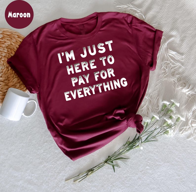 K&ouml;nnte beinhalten: Ein T-Shirt in der Farbe Weinrot mit dem Aufdruck "I'm just here to pay for everything" in Wei&szlig;.