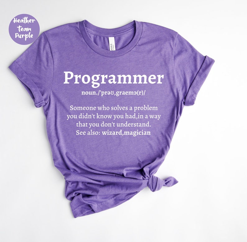 Puede incluir: Una camiseta morada con la palabra "Programador" en blanco y una definici&oacute;n. La definici&oacute;n dice: "Alguien que resuelve un problema que no sab&iacute;as que ten&iacute;as, de una manera que no entiendes."
