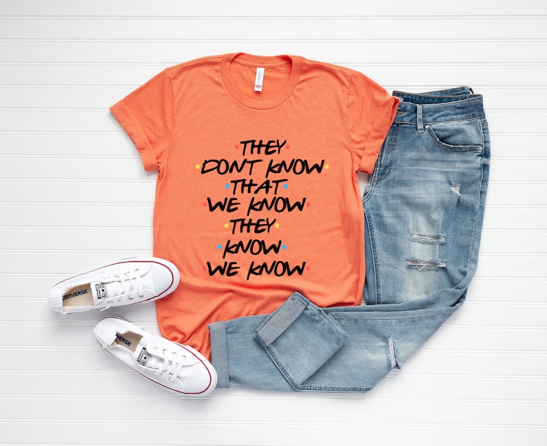 May include: Orange t-shirt with the text "They don't know that we know they know we know" in black with colorful dots.
