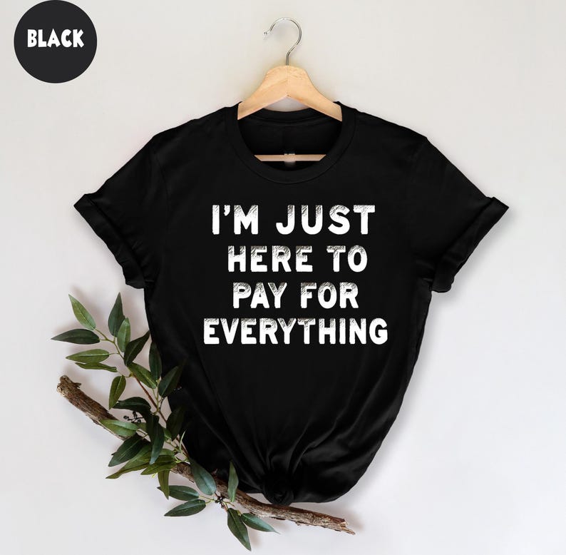 K&ouml;nnte beinhalten: Schwarzes T-Shirt mit dem Text "I'm just here to pay for everything" in Wei&szlig;.
