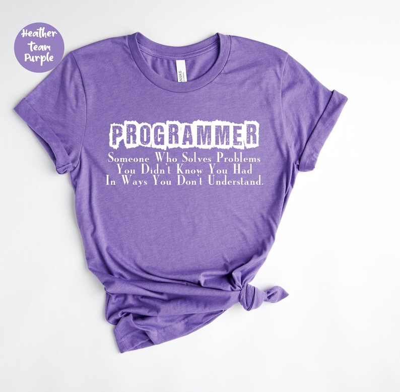 Puede incluir: Una camiseta morada con la palabra "PROGRAMADOR" en blanco, con un efecto desgastado. El texto de abajo dice: "Alguien que resuelve problemas que no sab&iacute;as que ten&iacute;as, de formas que no entiendes."