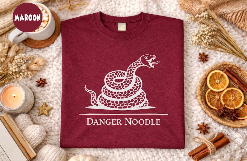 Funny snake themed graphic t shirt featuring a “Danger Snake” concept inspired by ball python humor. The design uses playful exaggeration to turn a typically misunderstood reptile into a lighthearted joke. Suitable for casual daily wear, reptile expos, relaxed outings, or as a gift for snake owners and exotic pet lovers who enjoy humorous animal designs.