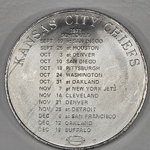 May include: A silver coin with the text "KANSAS CITY CHIEFS" around the edge. The coin lists the 1971 football schedule for the Kansas City Chiefs.