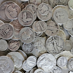 Könnte beinhalten: Eine Ansammlung von Silbermünzen, darunter Half Dollars und Dimes, liegt auf einer Oberfläche. Die Münzen zeigen verschiedene Designs und Inschriften, mit sichtbaren Daten und Phrasen wie "In God We Trust" und "Liberty".