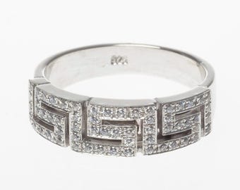 Puede incluir: Un anillo de banda de plata con un diseño geométrico engastado con pequeños diamantes transparentes.