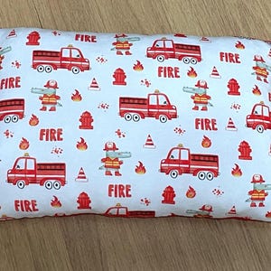 Könnte beinhalten: Rechteckiges Kissen mit weißem Hintergrund, bedeckt mit roten Feuerwehrautos, Hydranten, Flammen und Cartoon-Alligatoren in Feuerwehruniformen. Das Wort "FIRE" ist rot aufgedruckt.