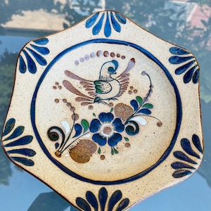 May include: A decorative ceramic plate with a blue and white border and a brown and blue bird with flowers in the center.