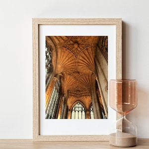 May include: A framed photograph of a cathedral interior with a vaulted ceiling and stained glass windows. The ceiling is made of wood and has a intricate pattern of arches and beams. The windows are tall and narrow, and they let in light that illuminates the interior of the cathedral.